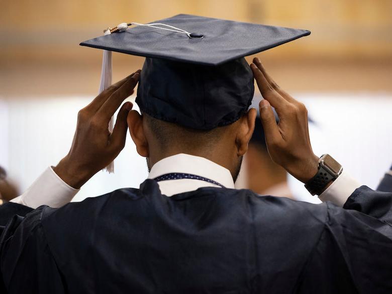 student putting on grad cap on their head